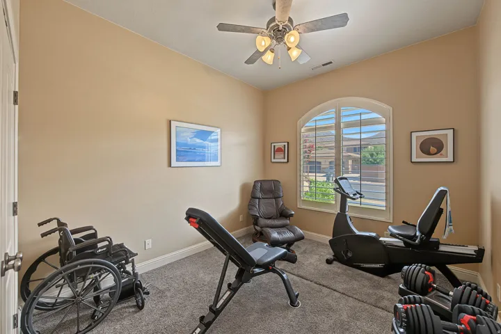 Arched window with plantation shutters, vaulted ceiling, and ceiling fan
