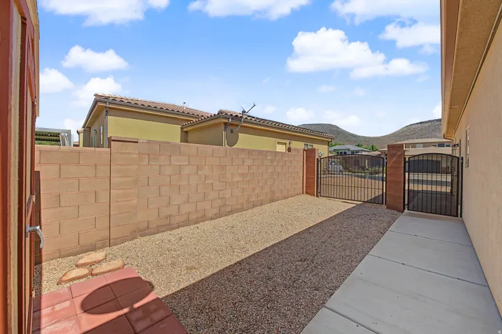 Private outdoor space featuring a block wall, gravel ground cover, and a wrought iron gate