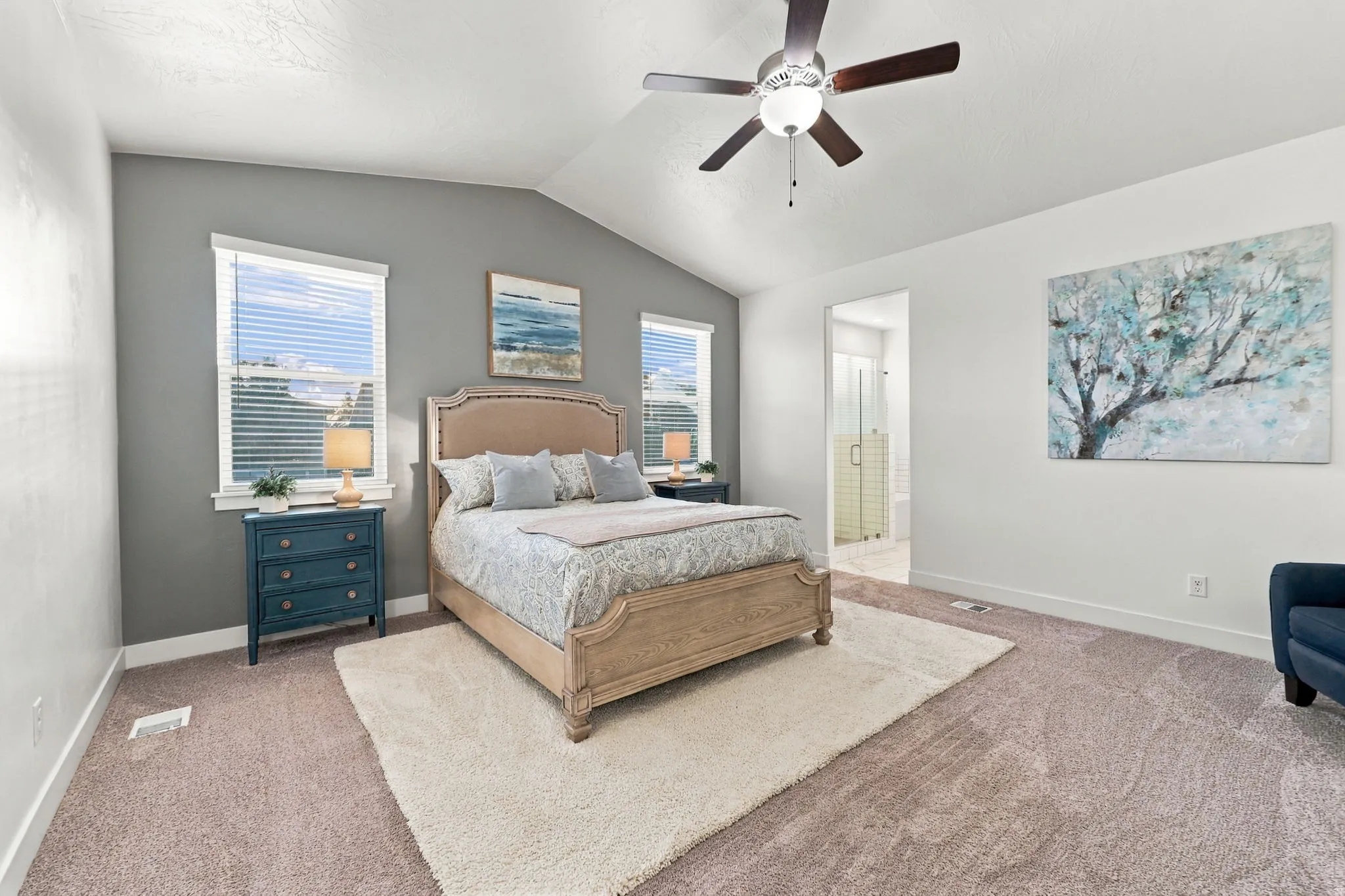 Vaulted ceiling with a ceiling fan, plush carpet, and two windows with blinds
