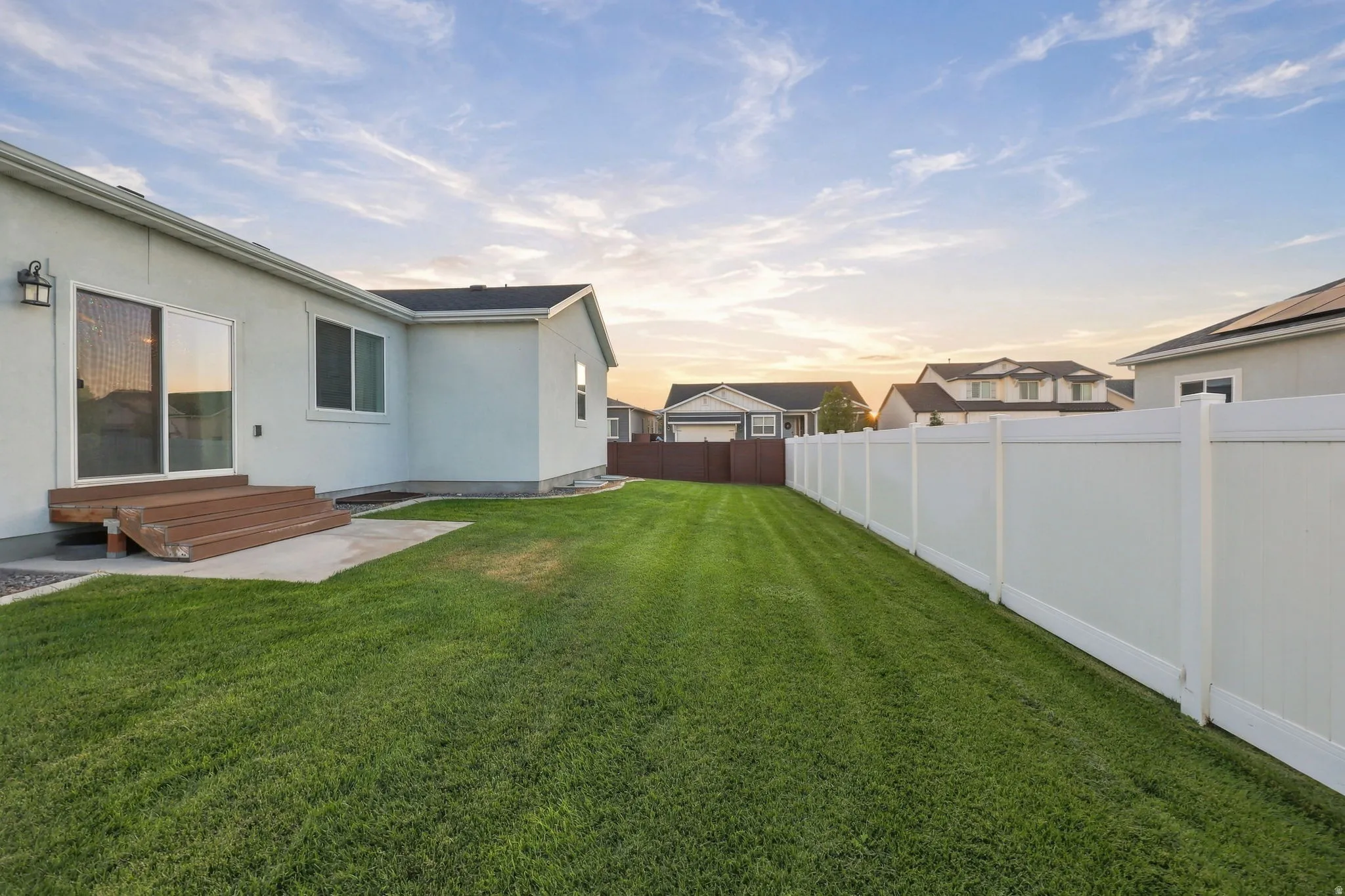 Manicured lawn with a privacy fence, concrete patio, and exterior lighting