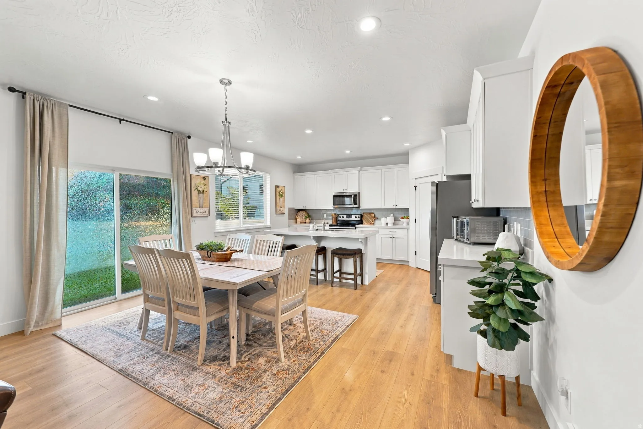 Open-concept living space with wood-finish flooring, recessed lighting, and a modern chandelier