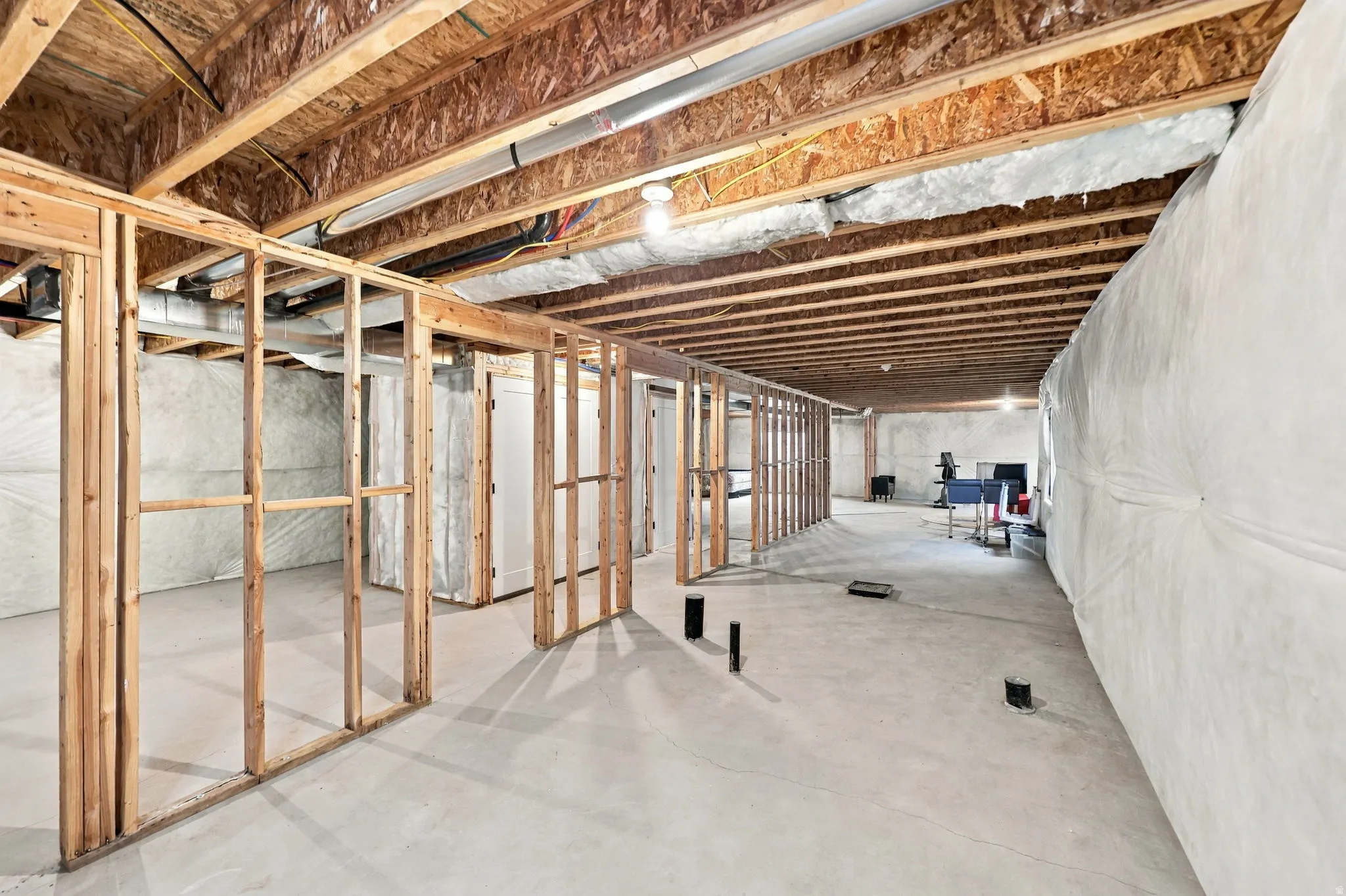 Expansive unfinished lower level featuring exposed wood joists and concrete flooring