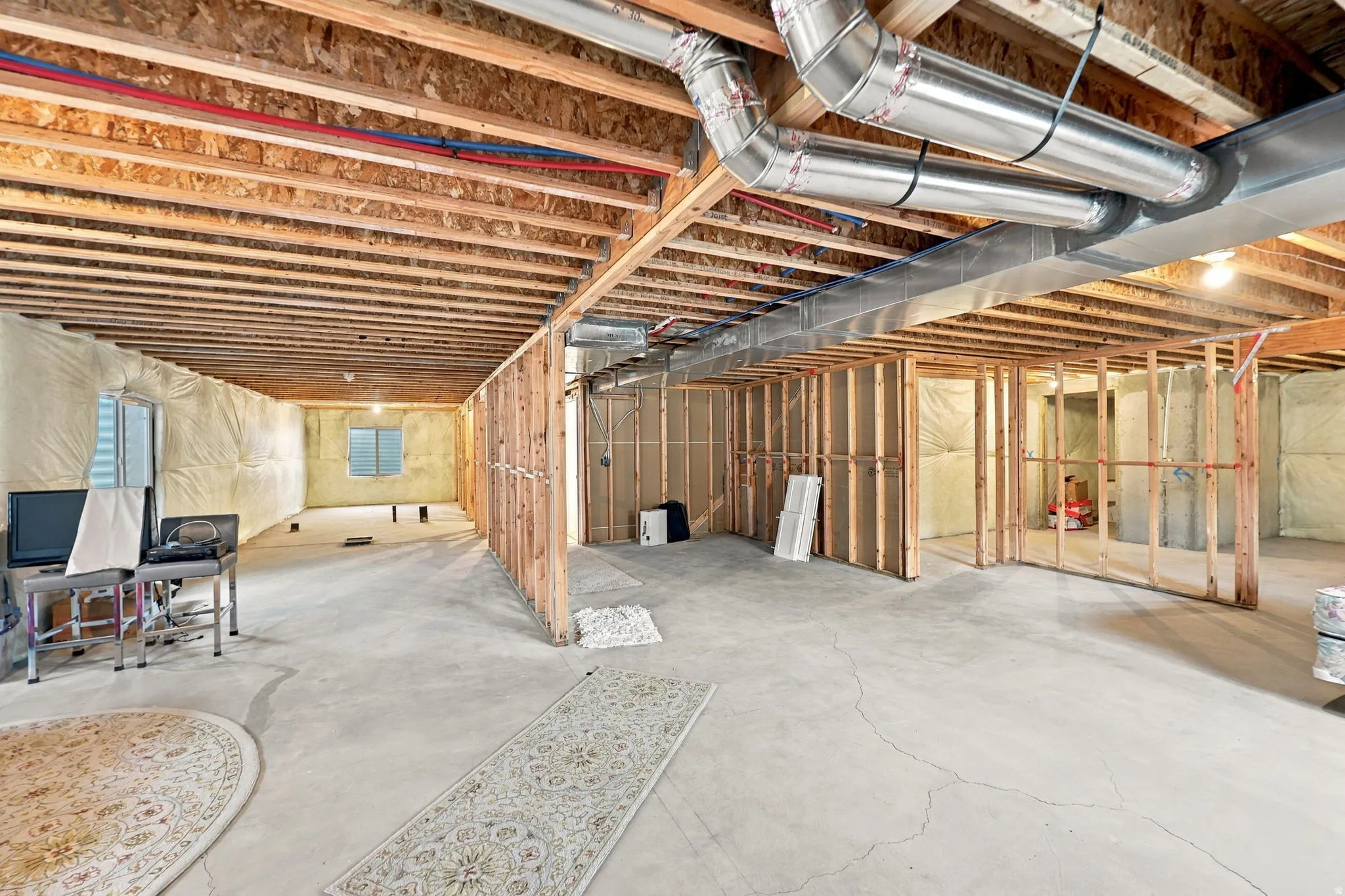 Unfinished lower level with wood beam ceiling and exposed ductwork