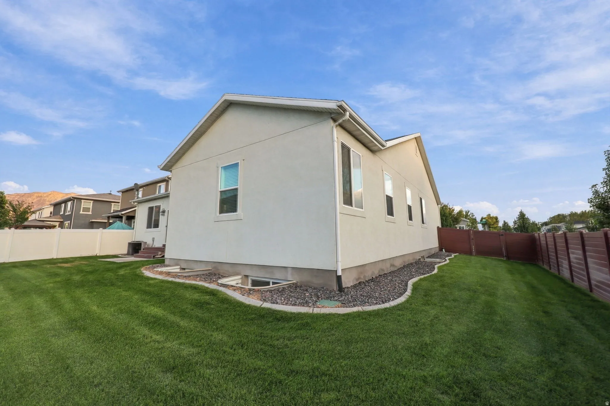 Expansive backyard featuring a manicured lawn, a white privacy fence, and a brown privacy fence