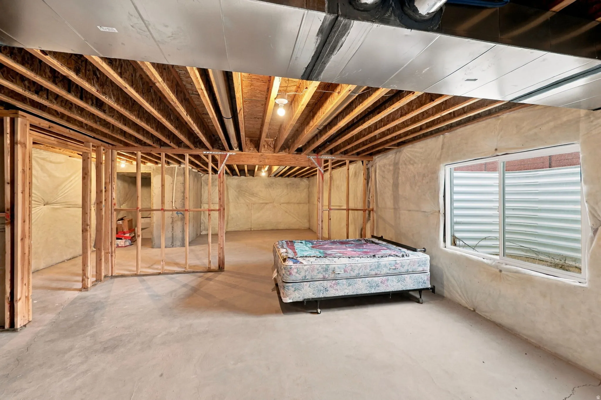 Framed interior walls, exposed ceiling joists, concrete flooring, and a single-pane window