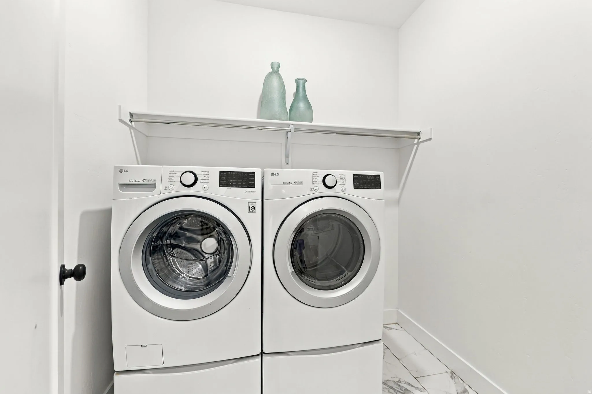 Laundry area featuring a wall-mounted shelf, modern washer and dryer, and white tile flooring