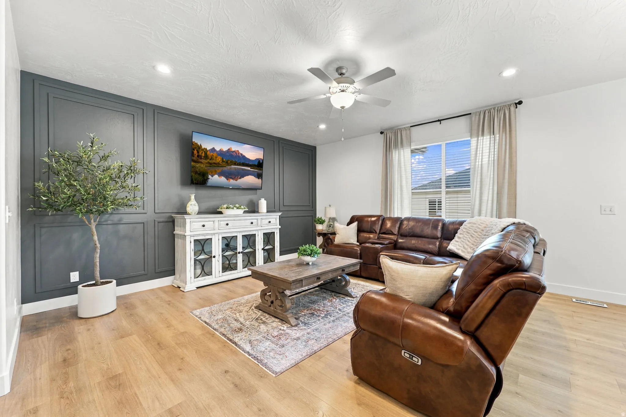 Accent wall with decorative paneling, wood-finish flooring, recessed lighting, and a ceiling fan with integrated lighting