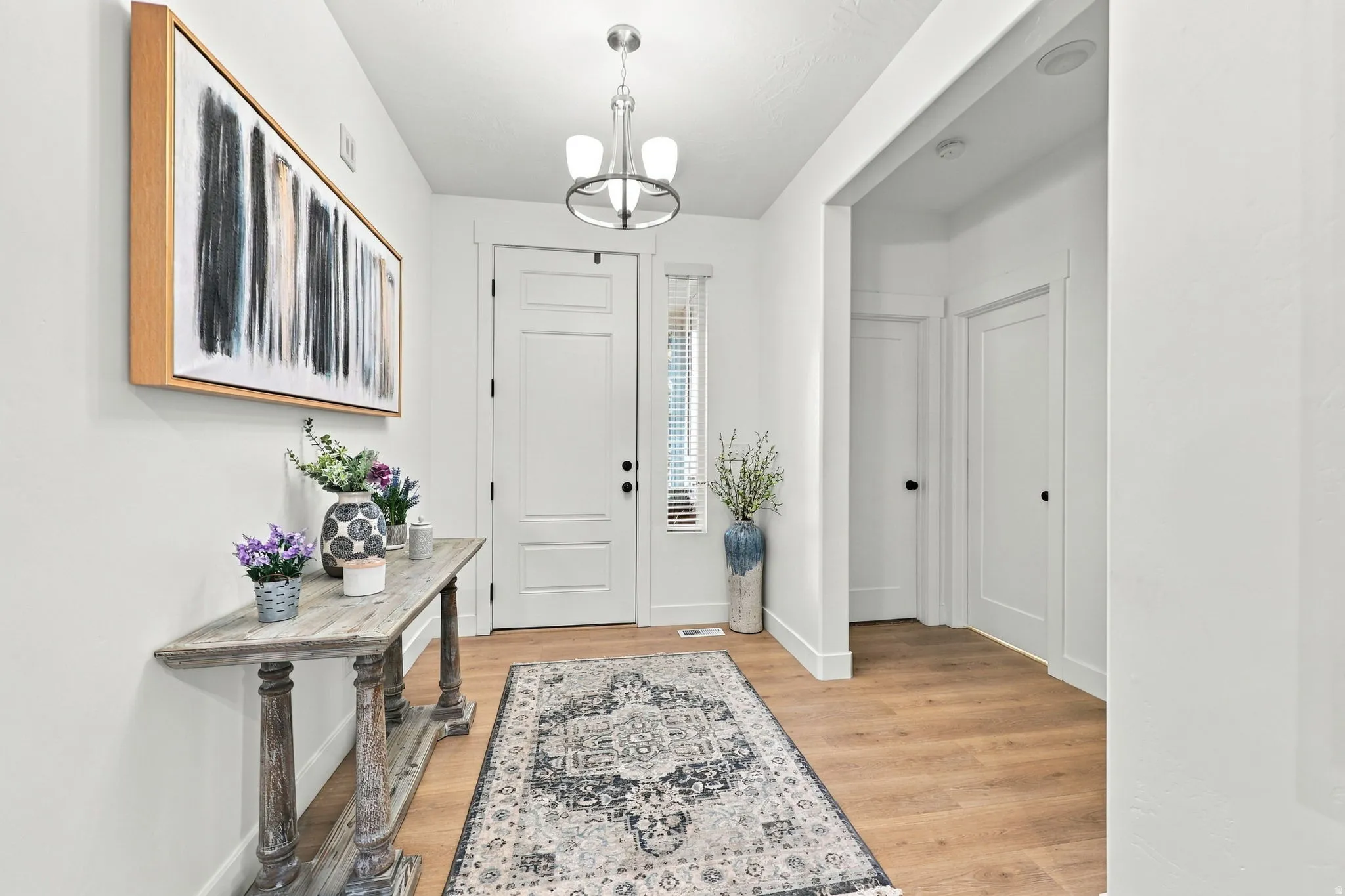 Entryway featuring wood-finish flooring, a white paneled door with black hardware, and a recessed window