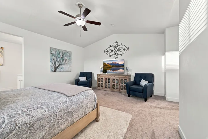 Vaulted ceiling, ceiling fan with integrated lighting, carpeted flooring, window with horizontal blinds, neutral wall tones