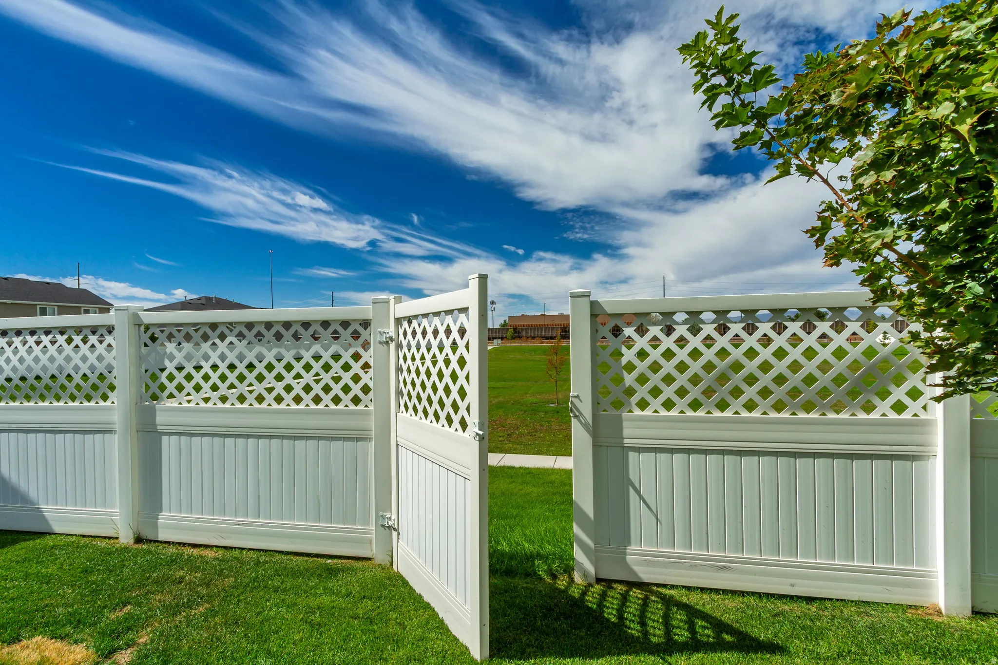 White lattice-top fencing with a matching gate, bordered by a green lawn