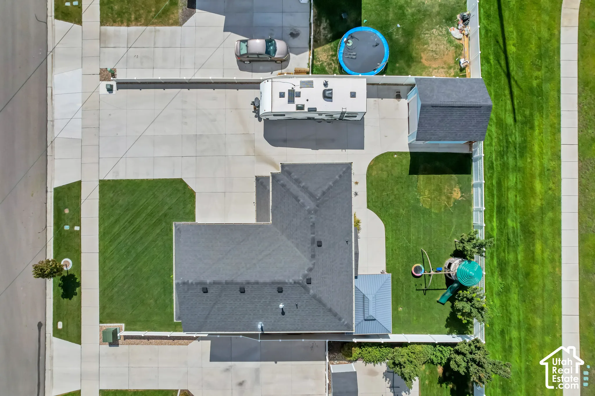 Expansive concrete driveway, detached garage structure, and a well-maintained lawn area