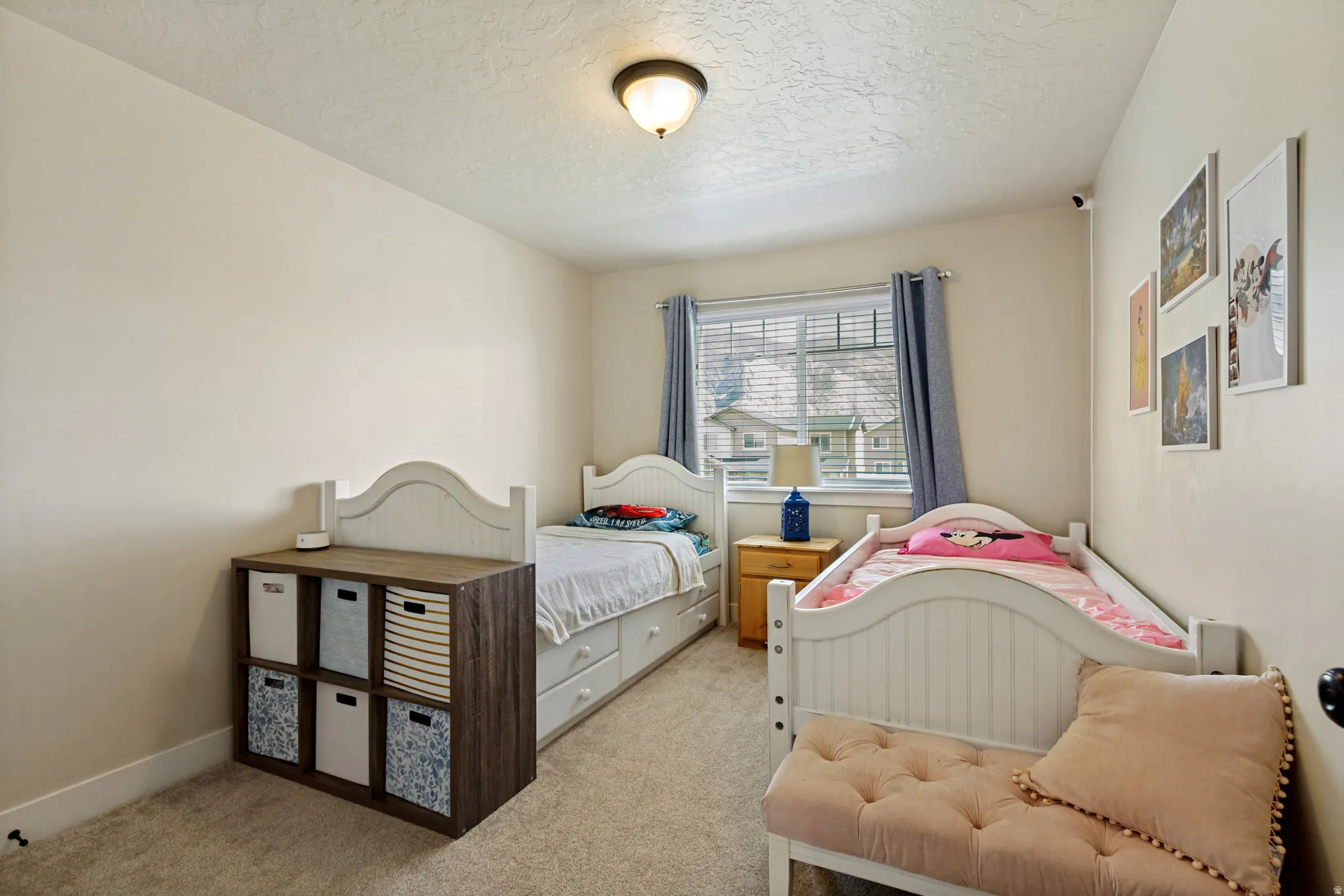 Light-toned walls with textured ceiling, warm-toned carpeting, and a window with blinds
