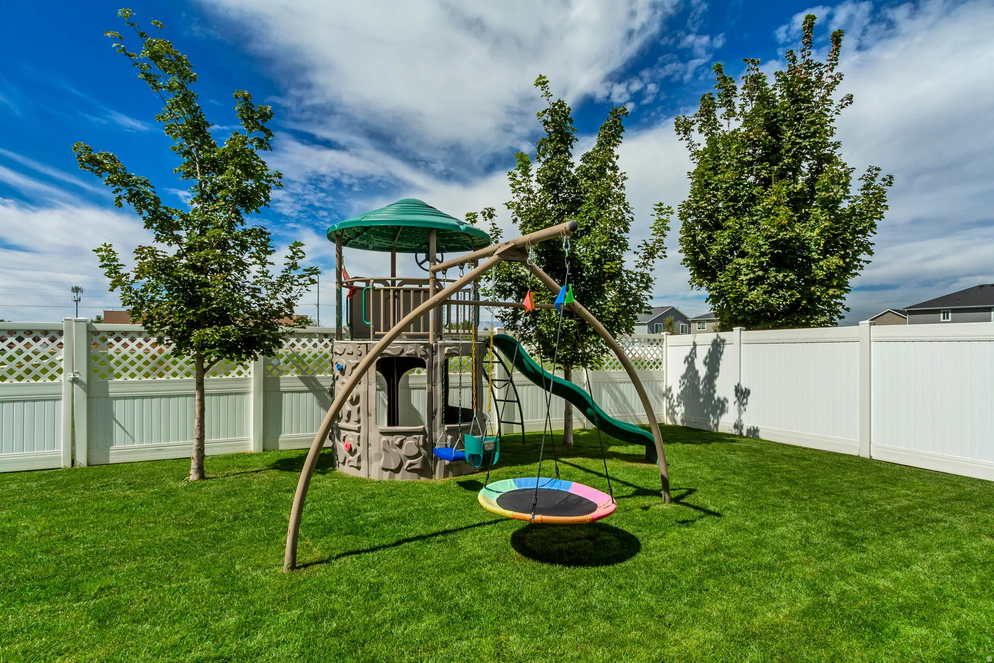Expansive green lawn with a white privacy fence and established trees
