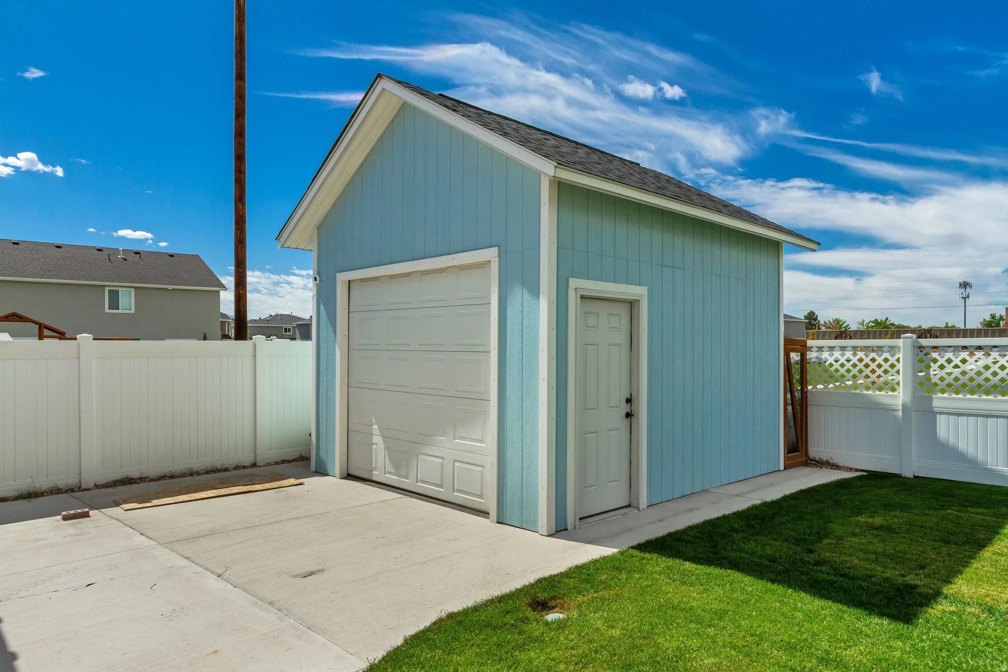Detached garage with a paneled overhead door, side entry door, and a shingle roof