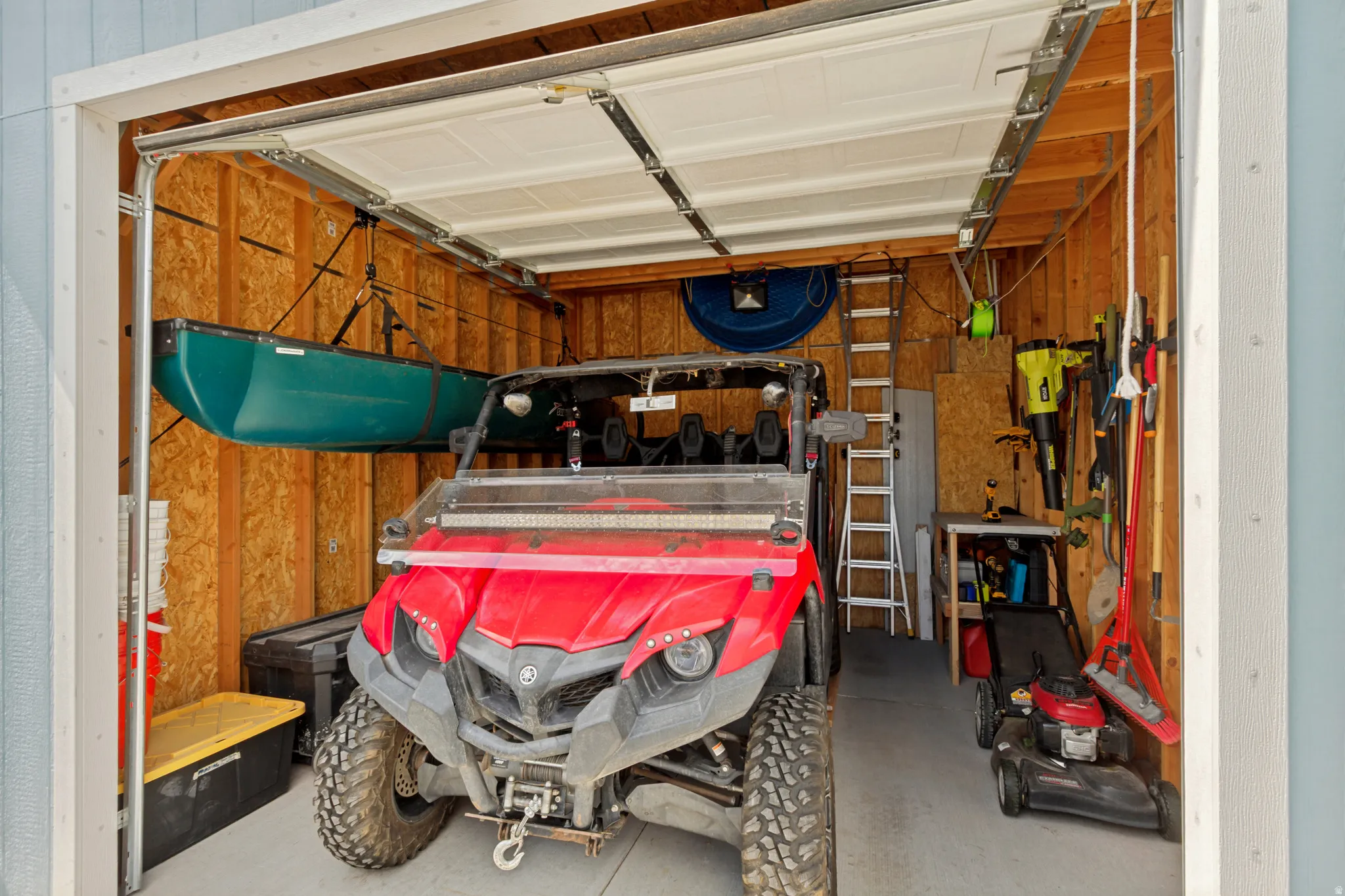Detached garage featuring wood paneling, an overhead garage door, and ample storage space