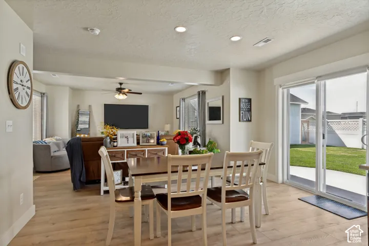 Dining area with laminate flooring throughout, recessed ceiling lighting, sliding glass door to exterior, ceiling fan, and window with blinds