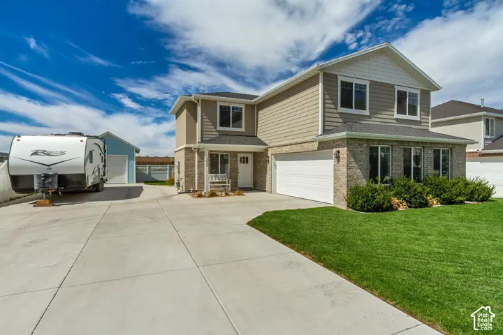 Two-story residence featuring a brick and siding exterior, an attached two-car garage, and a detached auxiliary garage with RV parking.