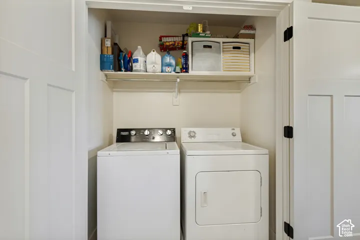 Dedicated laundry closet featuring a built-in shelf and hanging rod. Washer tray with floor drain.