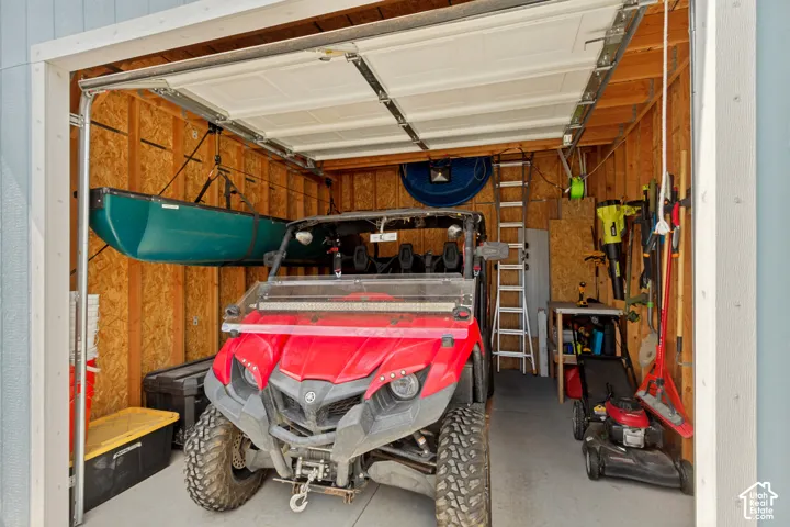 Shed/Workshop with exposed wood-paneled walls and a concrete floor. 15' +- feet deep. 13' +- wide. Manually operated overhead door.
