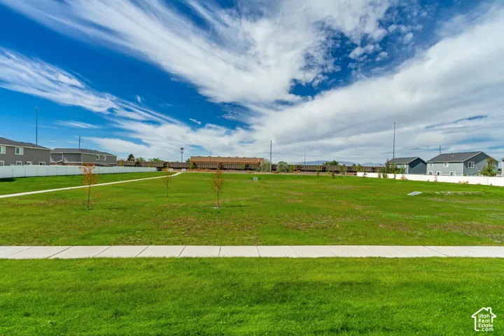 Expansive green space featuring a manicured lawn and a concrete walking path.