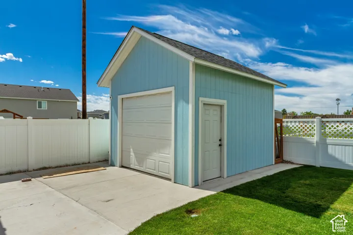 Detached garage featuring a paneled overhead door, a side entry door, and light blue vertical siding