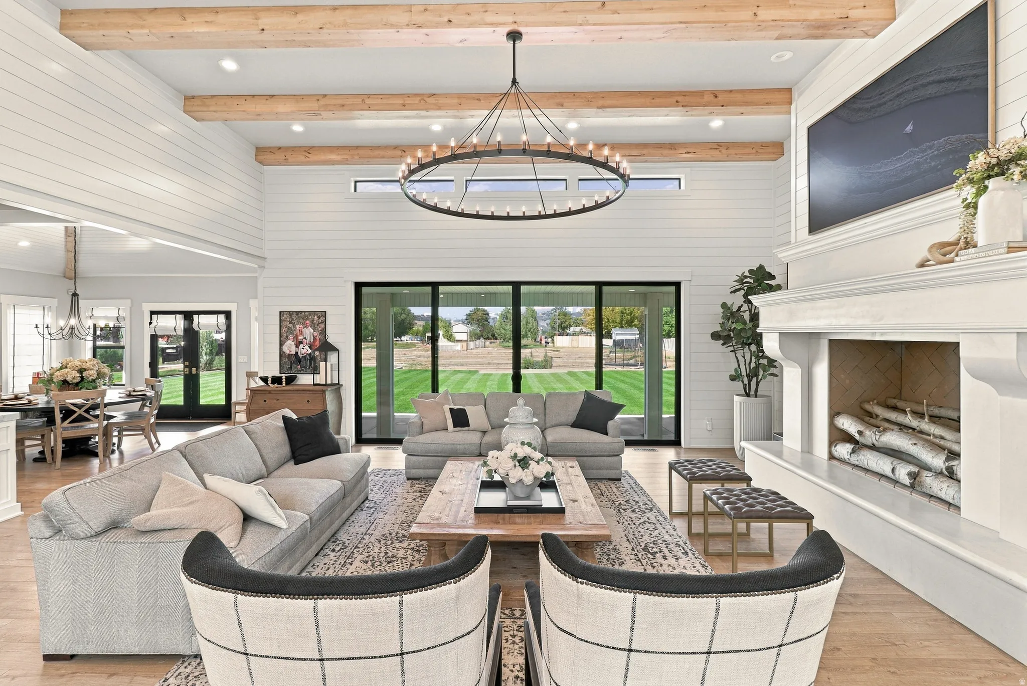 Vaulted ceilings with exposed wood beams, a prominent white mantel fireplace, and a large sliding glass door