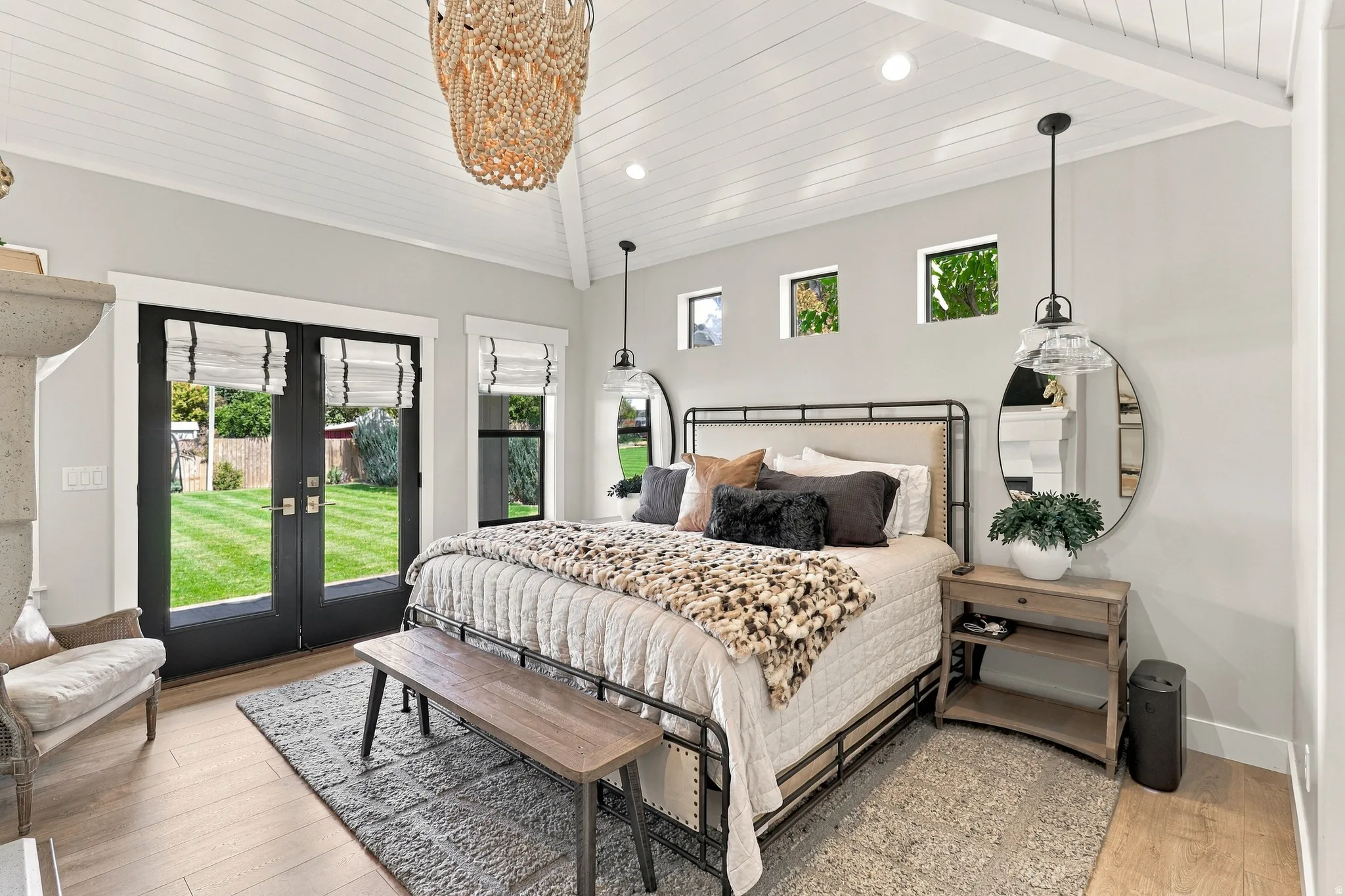 Vaulted wood-paneled ceiling with exposed beams, wood-finish flooring, black French doors, three transom windows, and a built-in fireplace