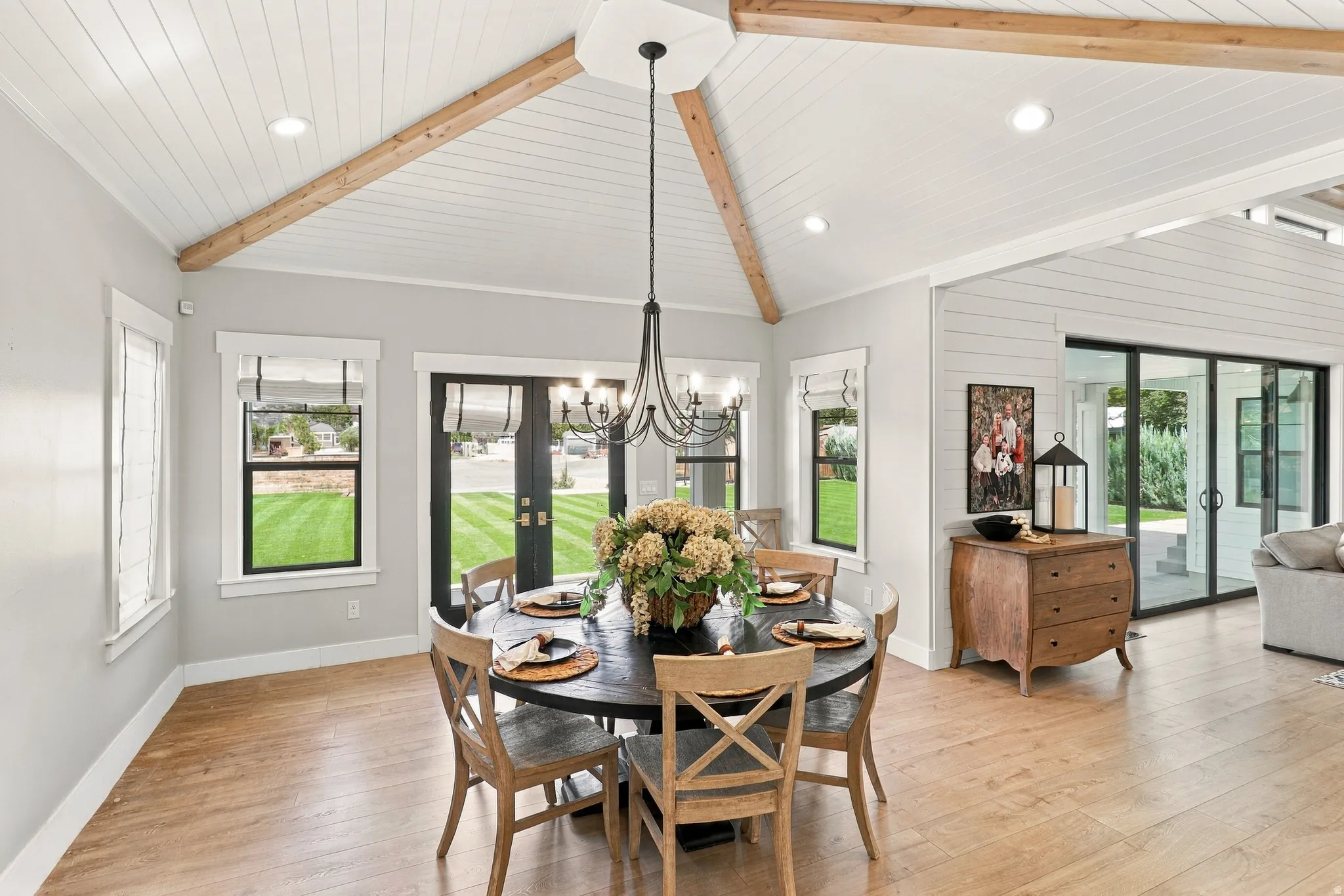 Vaulted ceiling with exposed wood beams, shiplap ceiling finish, wood-finish flooring, recessed lighting, and black-framed glass doors