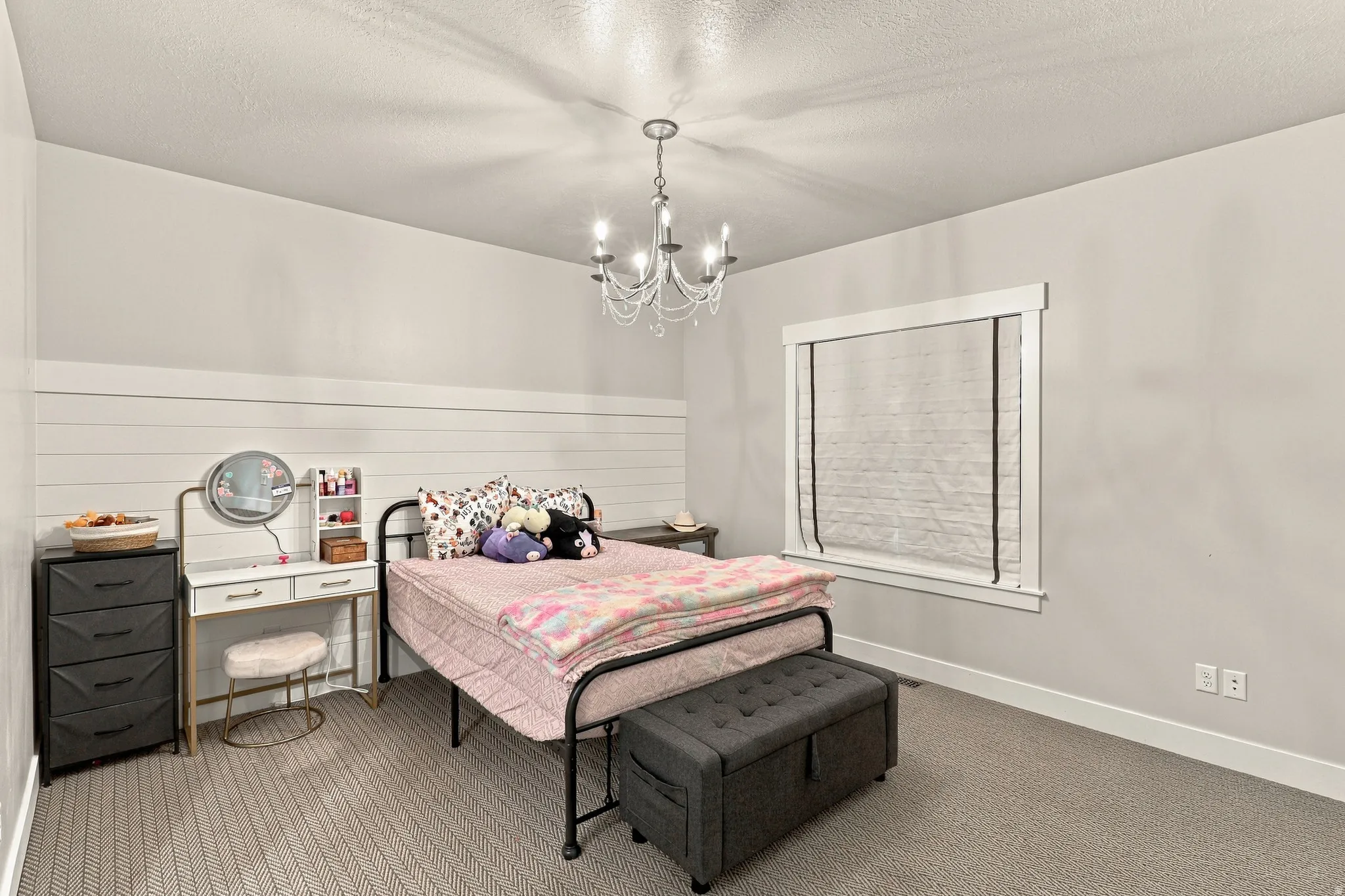 Carpeted flooring, white shiplap accent wall, chandelier lighting, and a window with white trim