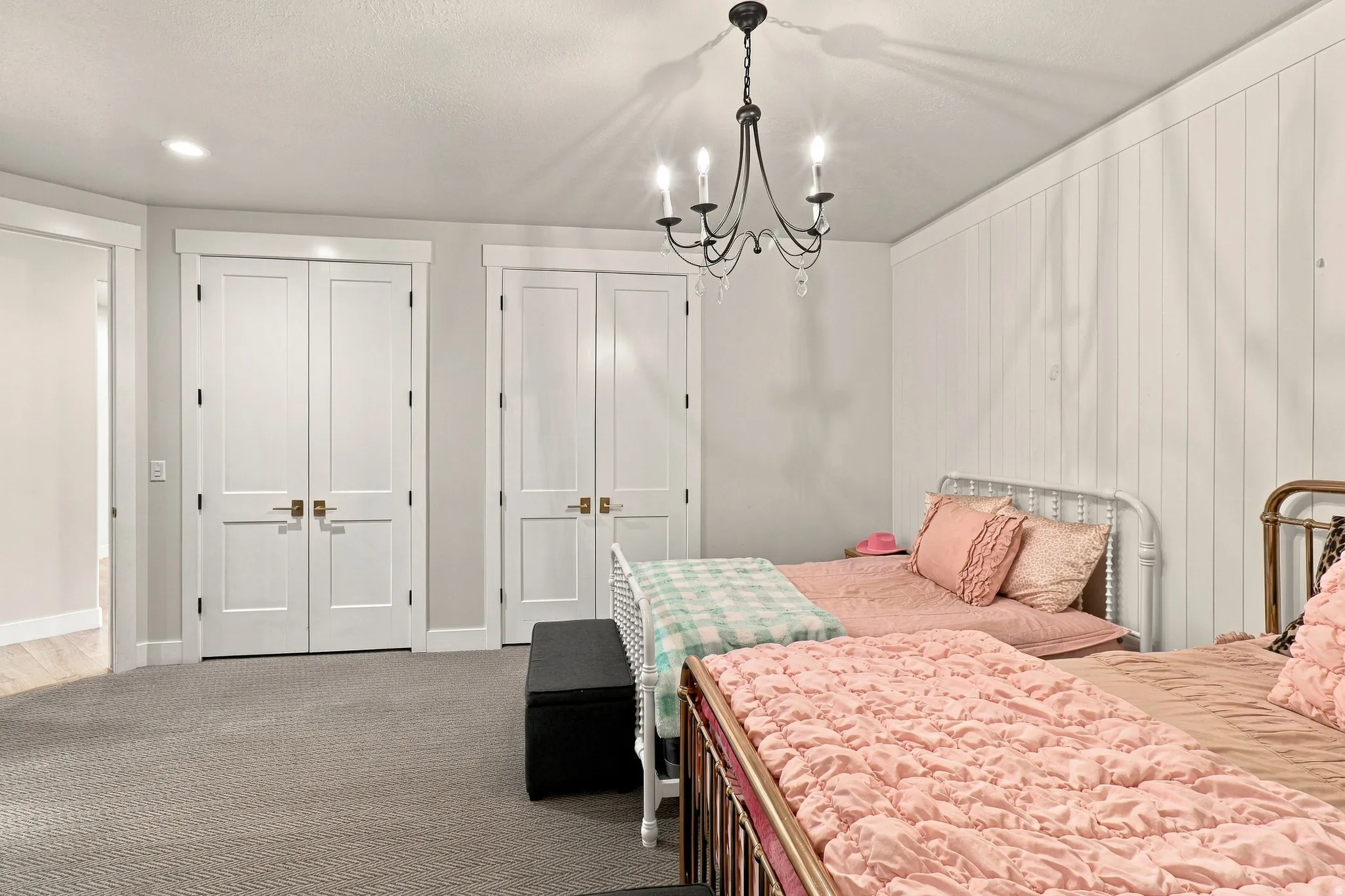 Recessed lighting, chandelier, board and batten wall, two sets of double-panel doors, and gray carpeting