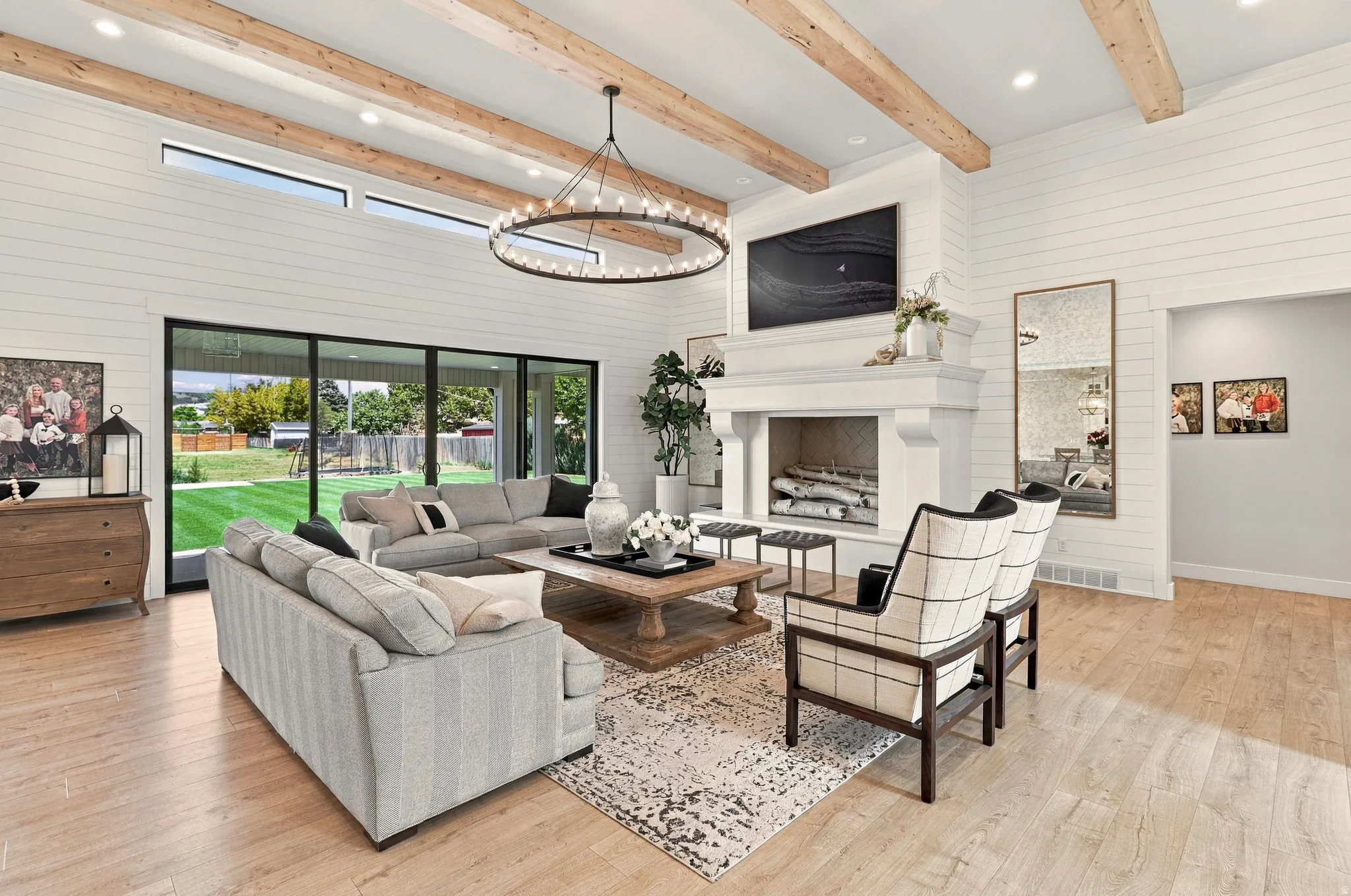 High ceilings with exposed wood beams, a prominent fireplace with mantle, and wood-finish flooring