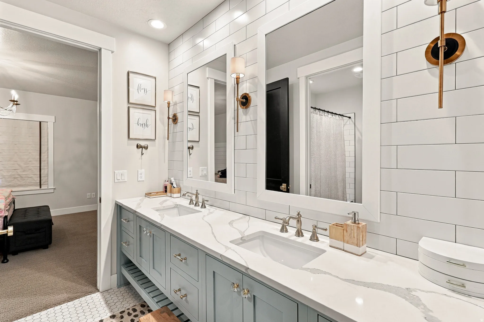 Dual vanity with integrated sinks, quartz countertop, light blue cabinetry, and white subway tile backsplash