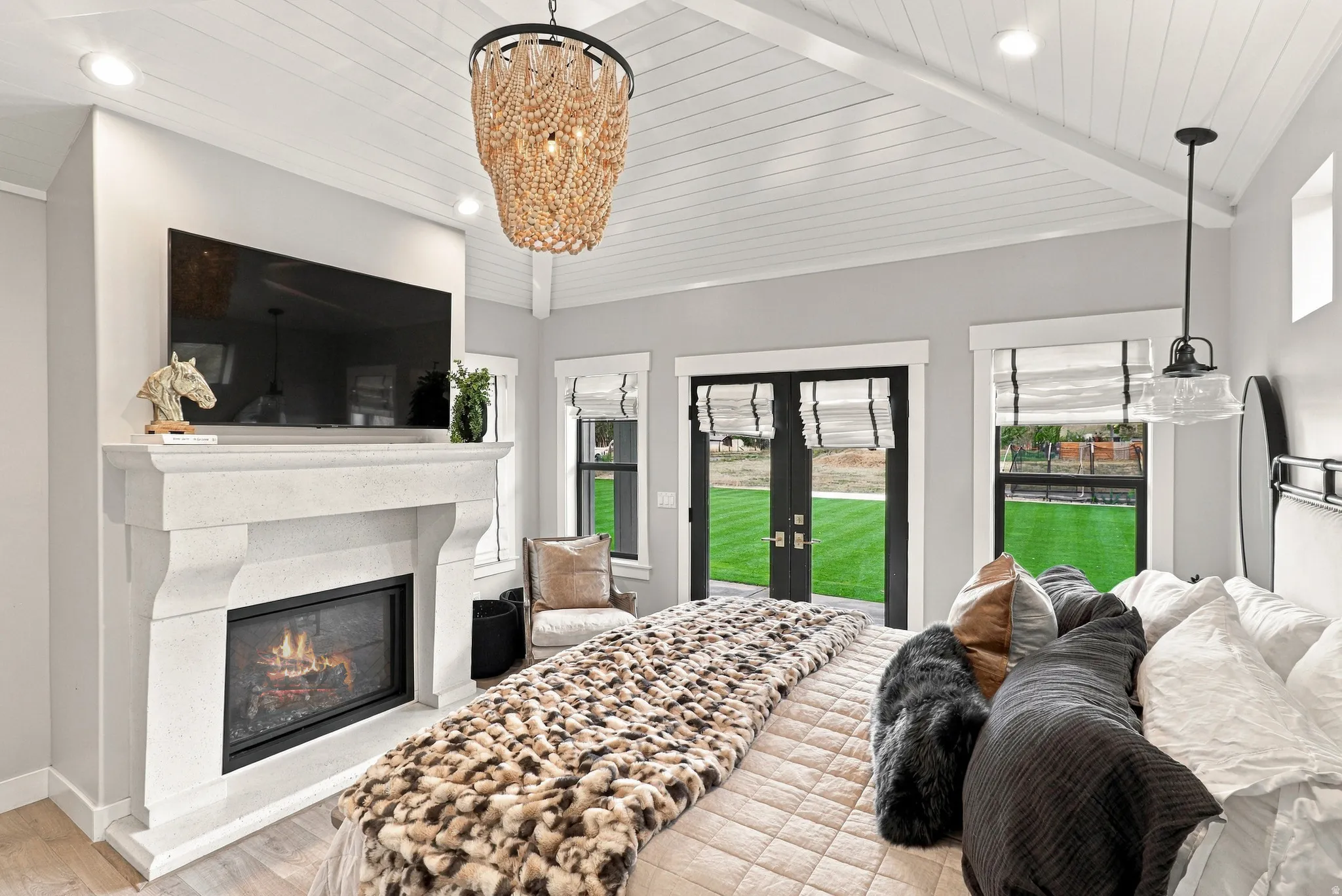 Vaulted planked ceiling with exposed beams, recessed lighting, and a beaded chandelier