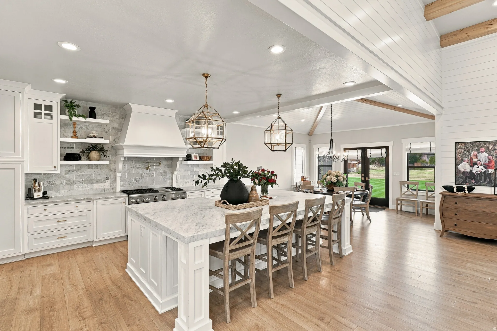 Kitchen featuring a large central island with seating, white cabinetry, a tile backsplash, and wood-finish flooring