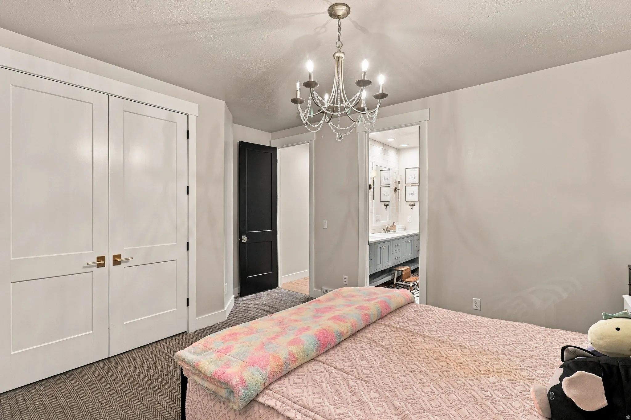 White paneled closet doors with bronze hardware, dark paneled interior door, and a crystal chandelier