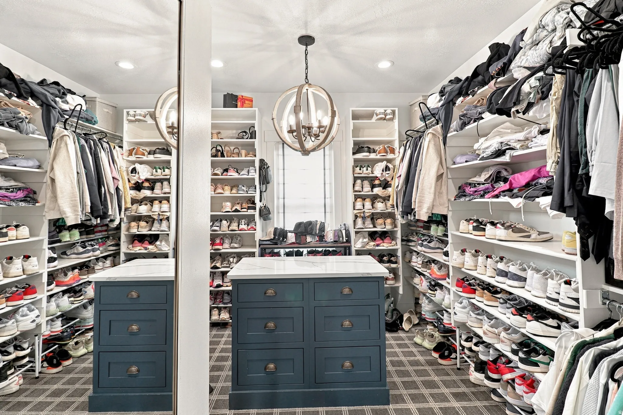 Custom built-in shelving, center island with drawer storage and stone top, recessed lighting, chandelier, and patterned floor covering
