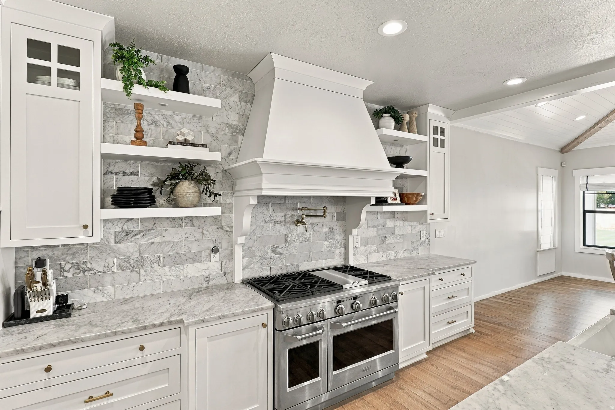 Stainless steel range, white shaker cabinetry, stone countertops, stone tile backsplash, and recessed lighting