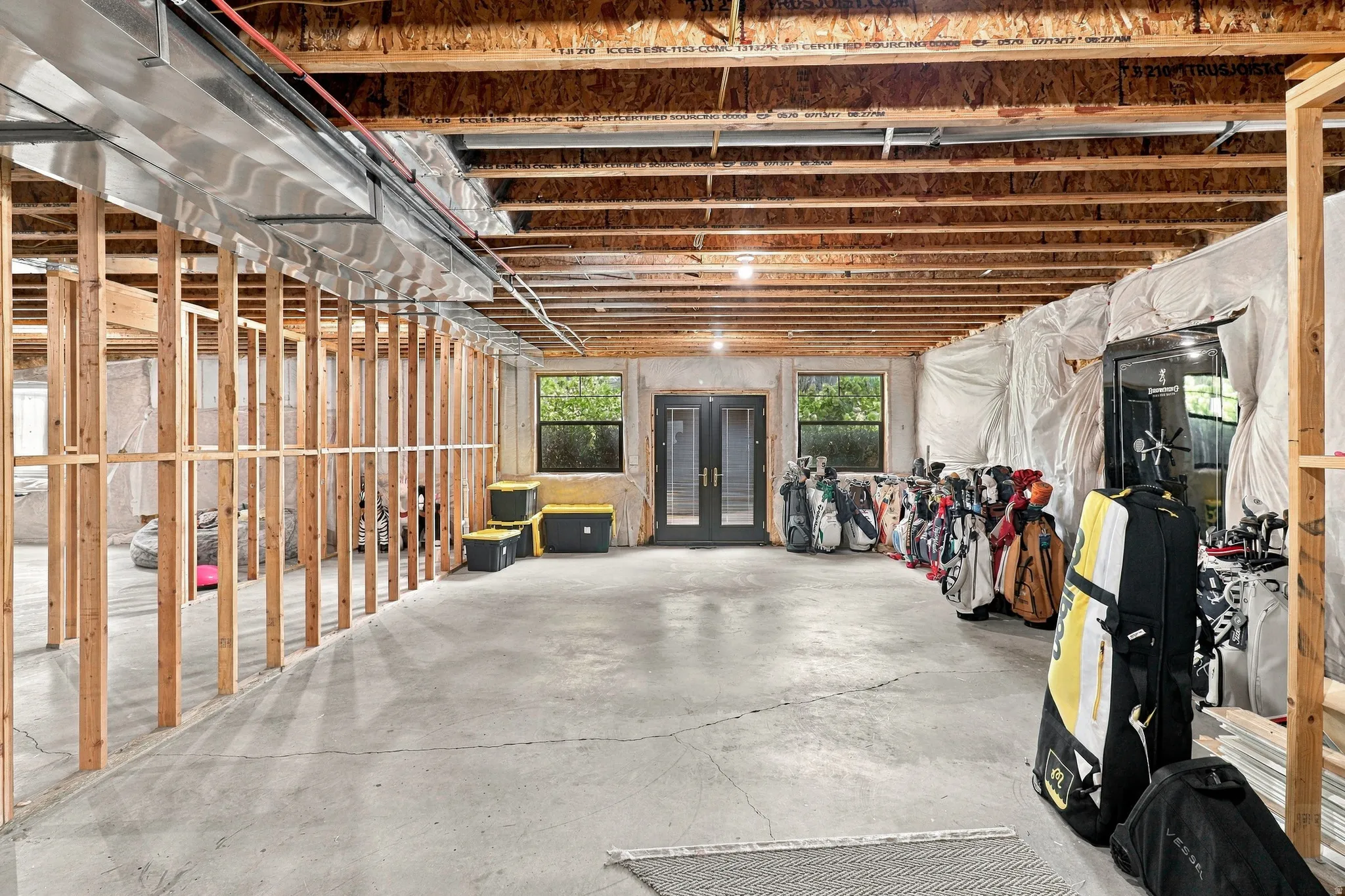 Unfinished basement with concrete flooring, exposed wood joists, and framed interior walls