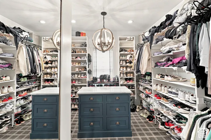 Custom built-in shelving, center island with drawer storage and stone top, recessed lighting, chandelier, and patterned floor covering