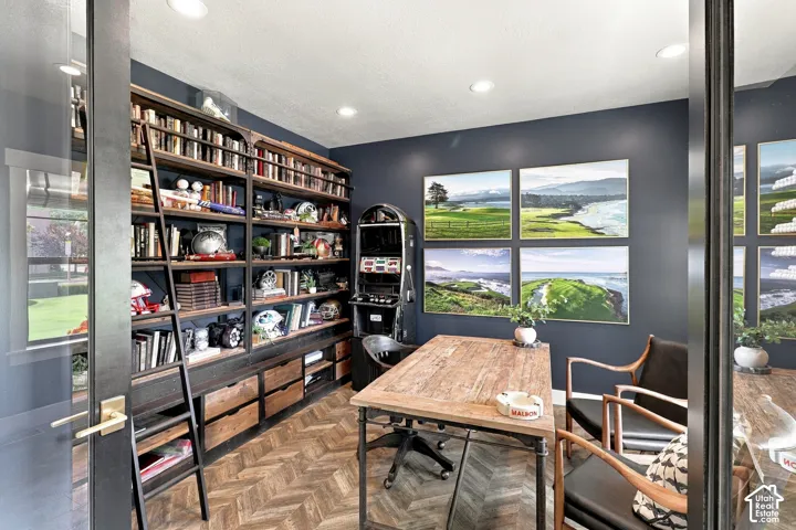 Herringbone wood-finish flooring, extensive built-in shelving with a rolling ladder, recessed ceiling lighting, and a window with exterior views
