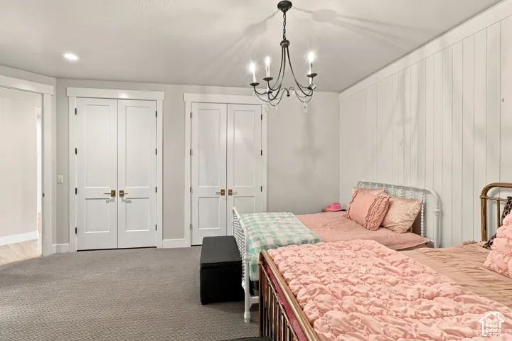 Recessed lighting, chandelier, board and batten wall, two sets of double-panel doors, and gray carpeting
