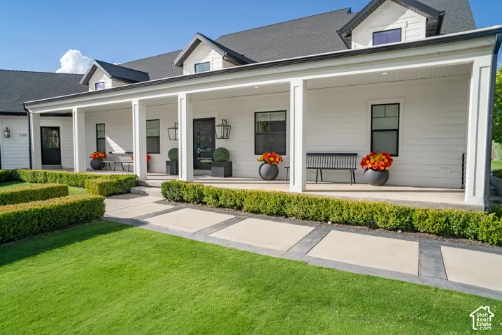 Expansive covered front porch with white columns, dark roof, and white siding