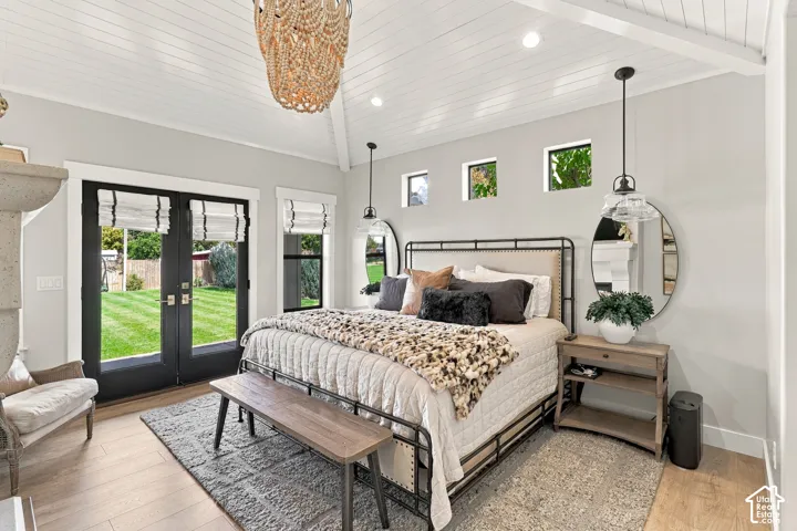 Vaulted wood-paneled ceiling with exposed beams, wood-finish flooring, black French doors, three transom windows, and a built-in fireplace