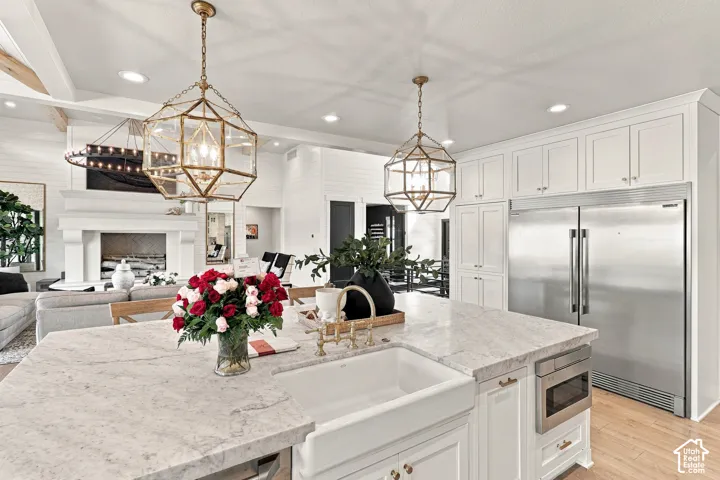 Spacious kitchen island with a farmhouse sink, stainless steel built-in microwave, and pendant lighting