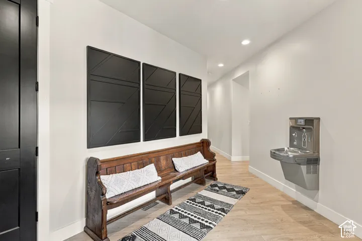Wood-finish flooring with recessed lighting, dark interior door, and a built-in drinking fountain