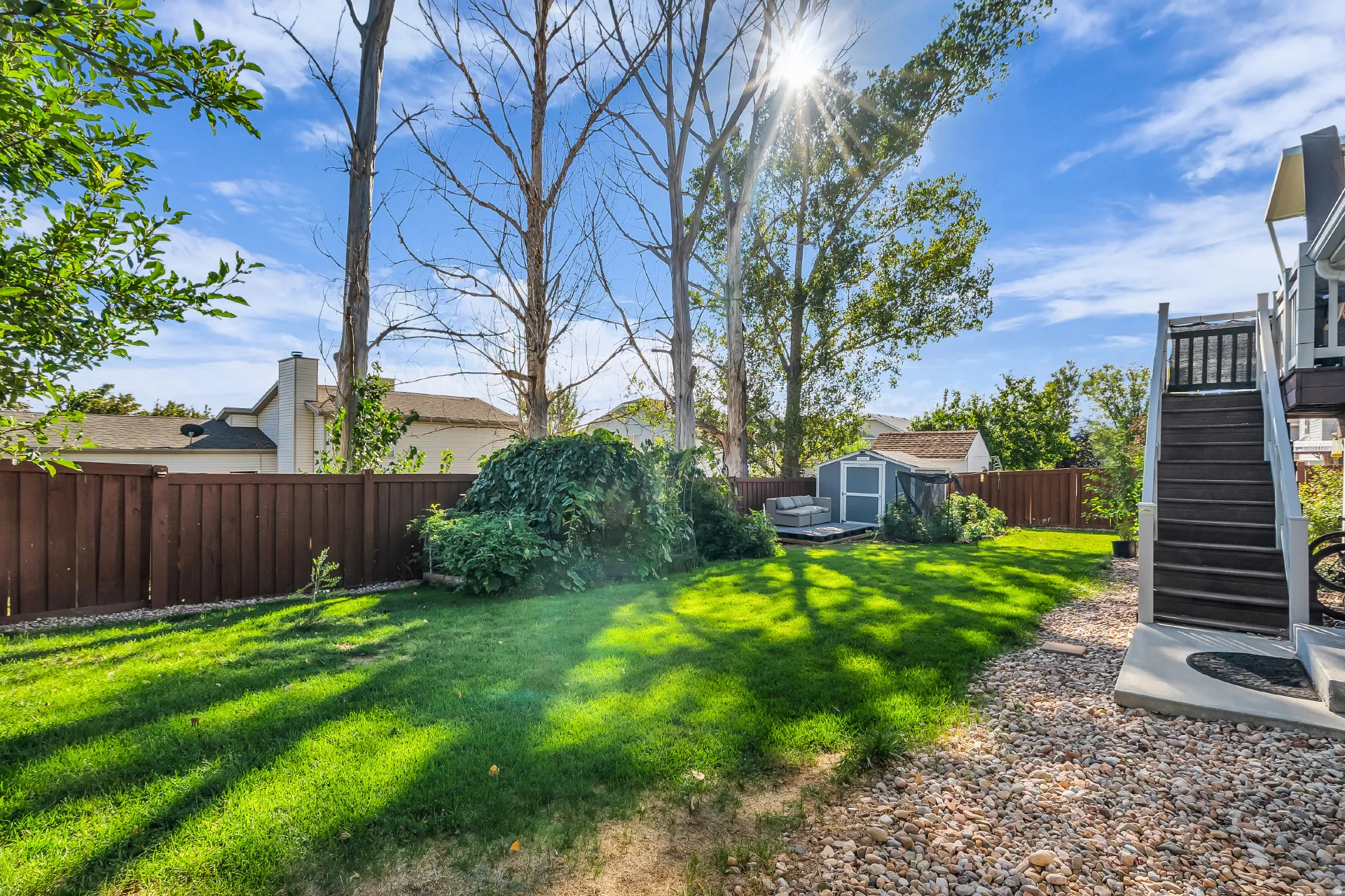 Expansive backyard featuring arch of grapevines, manicured lawn, and a privacy fence
