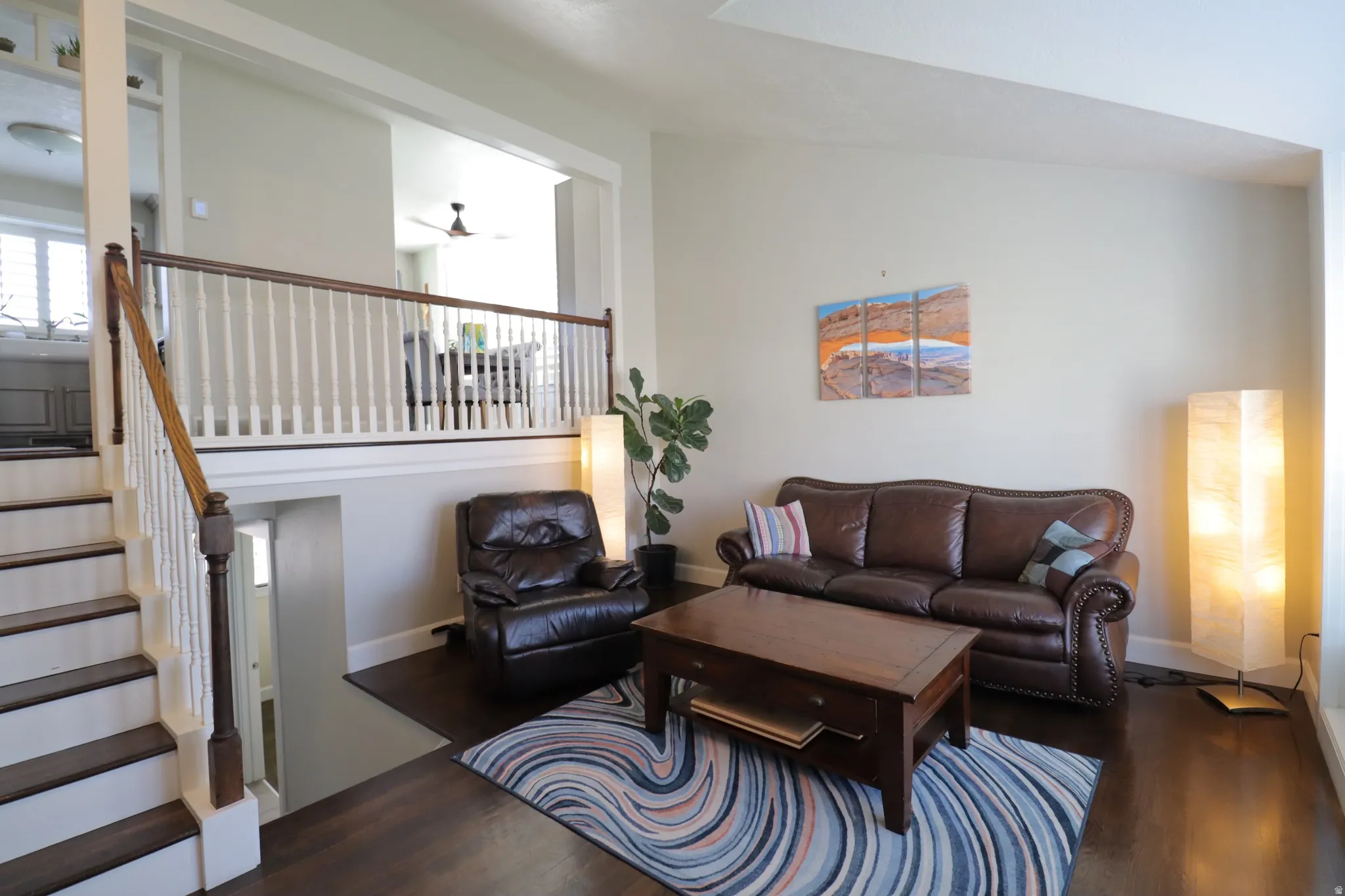 Living room with stairs that lead to open kitchen and dining area.