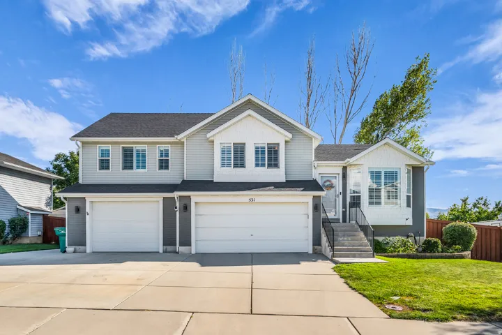 Multi-level residence featuring a two-car garage, gray siding, and a bay window