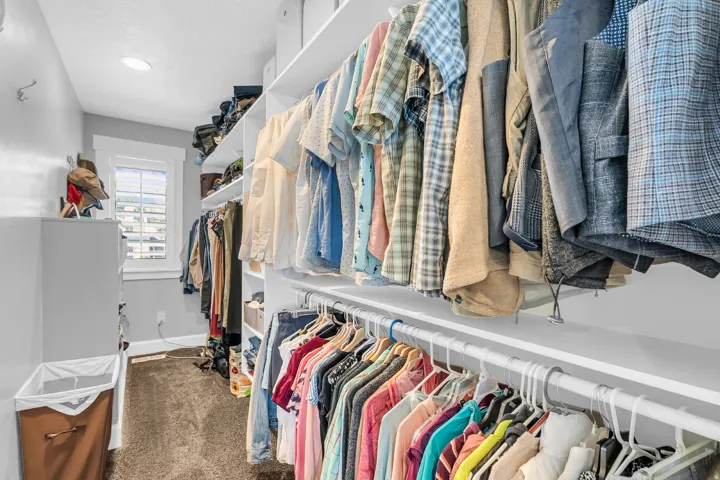 Walk-in closet featuring extensive built-in shelving, multiple hanging rods, and a window with plantation shutters