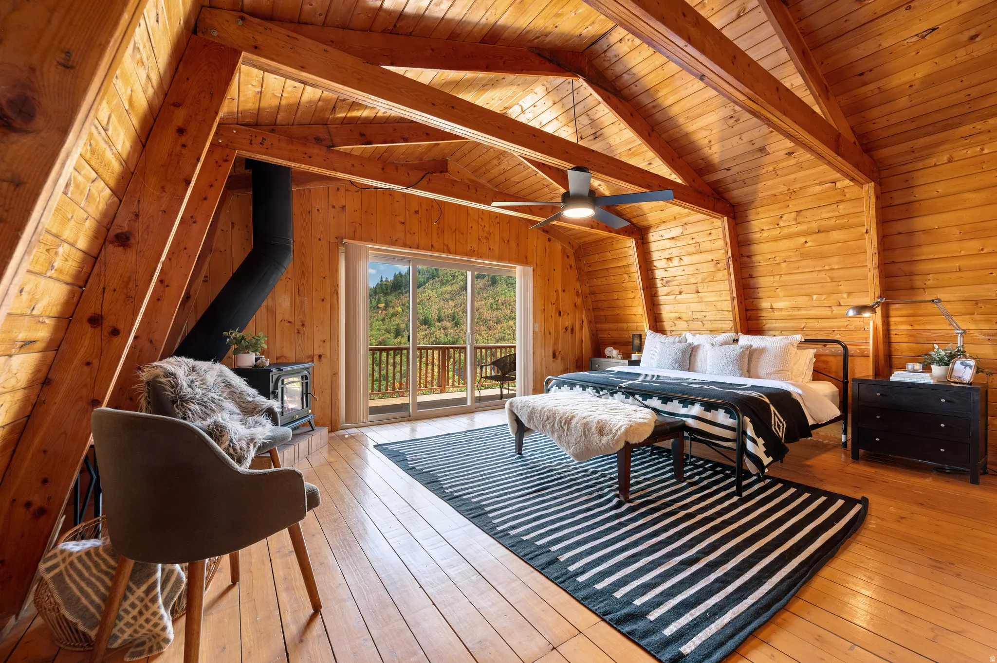 Soaring cathedral ceilings with exposed wood beams frame this light-filled primary bedroom suite